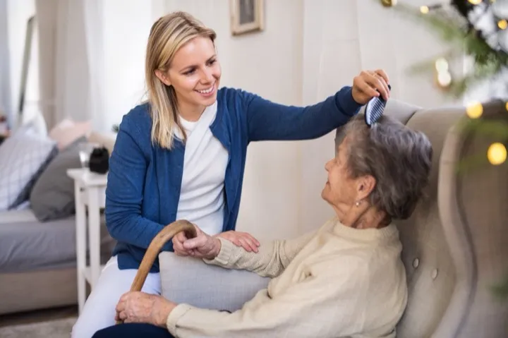Caring staff member providing gentle grooming assistance to senior resident at Archwood Assisted Living